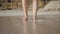 Beautiful women feet standing on the beach sand with a white skin tone and brown rocks