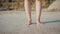 Beautiful women feet standing on the beach sand with a white skin tone and brown rocks