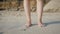 Beautiful women feet standing on the beach sand with a white skin tone and brown rocks