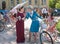 Beautiful women in old fashion dresses talking about vintage bicycle during outdoor festival Retro Cruise