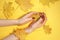 Beautiful women`s hands on paper yellow background, autumn hand care concept