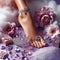 Beautiful women\\\'s legs with flowers and jewelry. The concept of spa, organic skin care. Female legs in petals