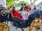 Beautiful women in traditional and colorful dress travelling in a horse drawn carriages at the April Fair, Seville Fair