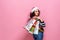 Beautiful women wearing bright Christmas carrying colorful shopping bags. On pink background. Christmas shopping And