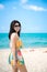 Beautiful women wearing sunglasses and colorful swimwear posing on the beach