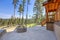 Beautiful wooden back porch with chairs on the hill and large backyard patio with fire pit and pine trees