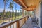 Beautiful wooden back porch with chairs on the hill and large backyard patio with fire pit and pine trees