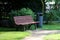a Beautiful wooden bench stands next to a metal trash can in a park