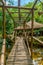 Beautiful wooden bridge over a small indigenous settlement lake, with a large wooden and straw hollow.