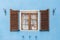 Beautiful wooden painted window with brown frames and white curtains and a cat and an orange wooden opened shutters and