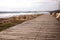 Beautiful wooden pedestrian walkway along the seashore. Footpath is paved with vintage boards. Natural wood planks on the beach