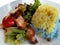 Beautiful yellow and blue rice, crispy pork, stir-fried chilies and fresh salad on a white plate