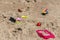 Beautiful yellow sandy beach with traces and footprints and a group of different colored children toys is by turquoise sea with