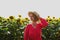 Beautiful yound woman in straw hat and red dress against sunflower field as natural background. Agricultural and harvesting