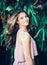 Beautiful young adult woman with natural teeth smile posing outdoors in tropical forest.