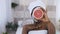 Beautiful young afro american woman in white towel on head applied facial clay mask while holding grapefruit halves on