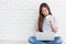 Beautiful young of Asian girl using a laptop while sitting at the floor in the living room and hold coffee, Asia women smile while