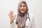 Beautiful young Asian muslim female doctor woman using stethoscope. Waving saying hello happy and smiling, friendly welcome