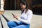 Beautiful young asian tourist. she is sitting on the stairs of a square while looking at the messages on her mobile phone