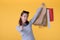 Beautiful young Asian woman with colourful shopping bags and credit card isolated on yellow background