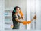 Beautiful young Asian woman, housewife wearing orange protective rubber gloves during cleaning