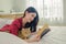 a beautiful young asian woman indulges in a good book while lying on her cozy bed, with her adorable cat nestled beside her.