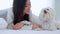 Beautiful young asian woman playful with fluffy dog shih tzu for relax with love on bed in bedroom at home.