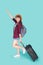 Beautiful young asian woman pulling suitcase isolated on blue background