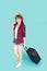 Beautiful young asian woman pulling suitcase isolated on blue background.