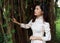 Beautiful young Asian woman  standing in the shadow of large banyan tree