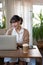 A beautiful young Asian woman working remotely at a cosy coffee shop, working on her laptop