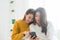Beautiful young asian women LGBT lesbian happy couple sitting on bed hug and using phone together bedroom at home.