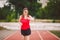 Beautiful young athlete Caucasian woman with big breast in red T-shirt and short shorts jogging, running in the stadium. Hairstyle