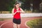 Beautiful young athlete Caucasian woman with big breast in red T-shirt and short shorts jogging, running in the stadium. Hairstyle