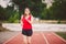 Beautiful young athlete Caucasian woman with big breasts in red T-shirt and short shorts jogging, running in the stadium with red