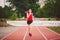 Beautiful young athlete Caucasian woman with big breasts in red T-shirt and short shorts jogging, running in the stadium with red