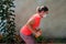 Beautiful young athlete wearing a white protective mask exercises with rubber dumbbells at home during coronavirus quarantine.