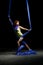 Beautiful young athletic girl, blue aerial silks on the light in the darkness