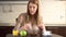 Beautiful young attractive casual woman having breakfast on her kitchen. Drinking orange juice.