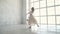 Beautiful young ballerina dancing in a light, flying dress on the background of a large window. the ballet dancer is