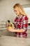 Beautiful young blond woman cooks coffee in kitchen