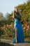 Beautiful young blond woman in the park with green trees and flowers