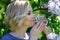 Beautiful young blond woman sniffing lilac bush