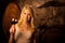 Beautiful young blond woman tasting red wine in a wine cellar