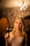 Beautiful young blond woman tasting red wine in a wine cellar