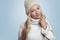 Beautiful young blond woman in white knitted sweater and hat smiling