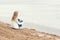 Beautiful young blonde girl in jeans and a white shirt sitting on the shore of the frozen cold of the lake near the forest in earl