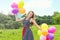 Beautiful young blonde girl smiles on a summer day walks with colored balls in the city