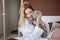 Beautiful young blonde girl in a Terry white robe in her apartment hugs her beloved cat.