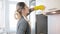 Beautiful young blonde woman cleaning dirty cupboards on kitchen